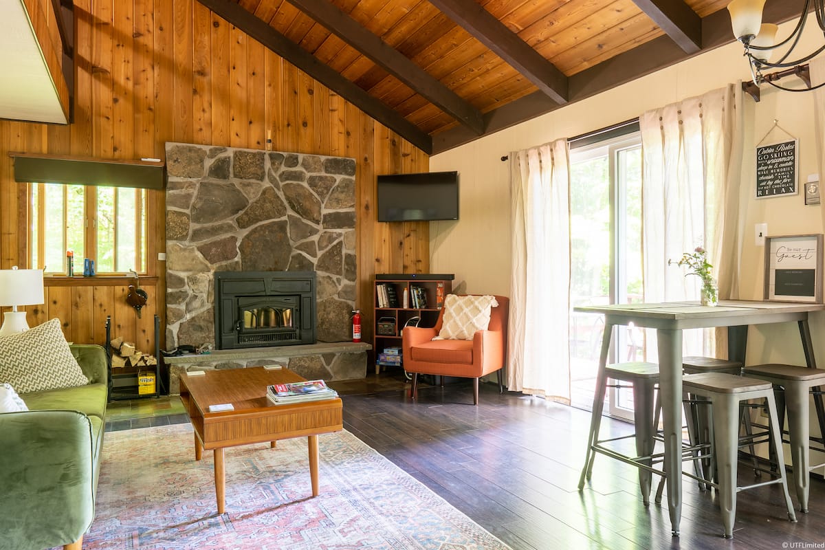 Living room with a stone fireplace, wood ceilings, and comfortable seating